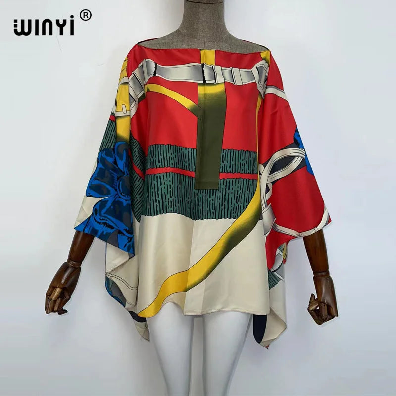 A woman models a colorful batwing abaya top featuring abstract patterns and a belted design.