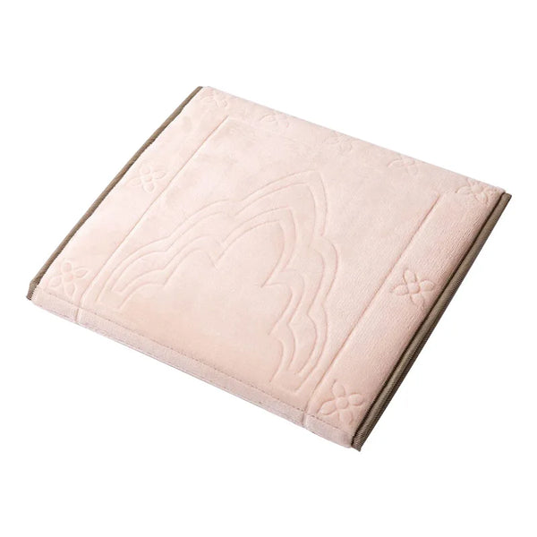 A square, light pink foldable Islamic prayer rug with embossed decorative patterns.