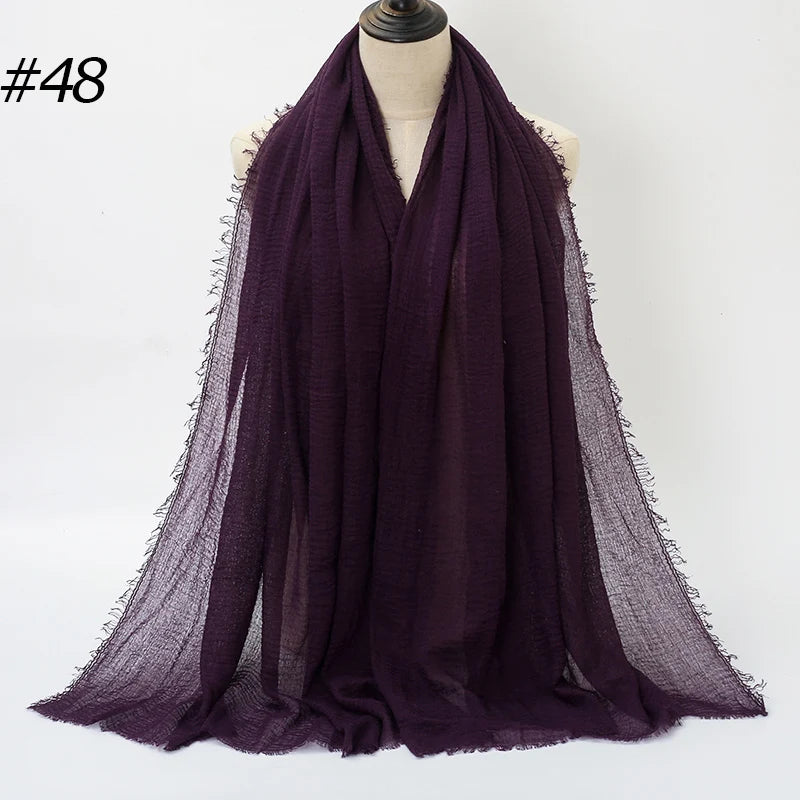 Ein tiefviolettes gekräuseltes Baumwoll-Hijab-Schal über einem Mannequin drapiert.