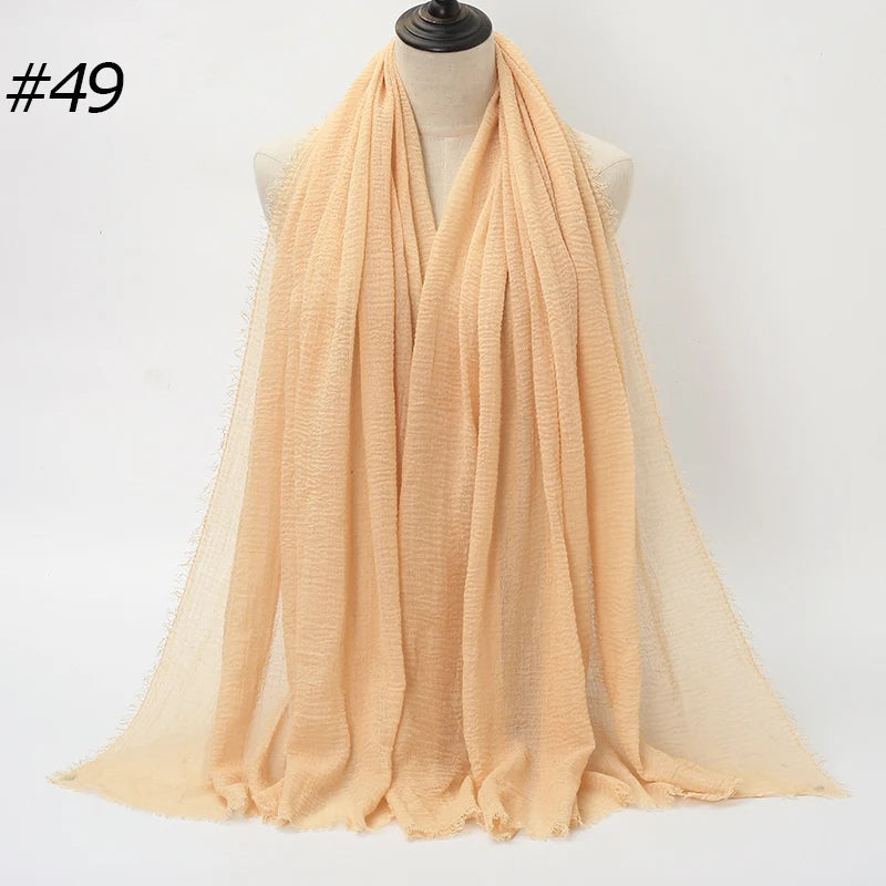 Helle Pfirsich-Crinkle-Baumwoll-Hijab-Schal über einem Mannequin drapiert.