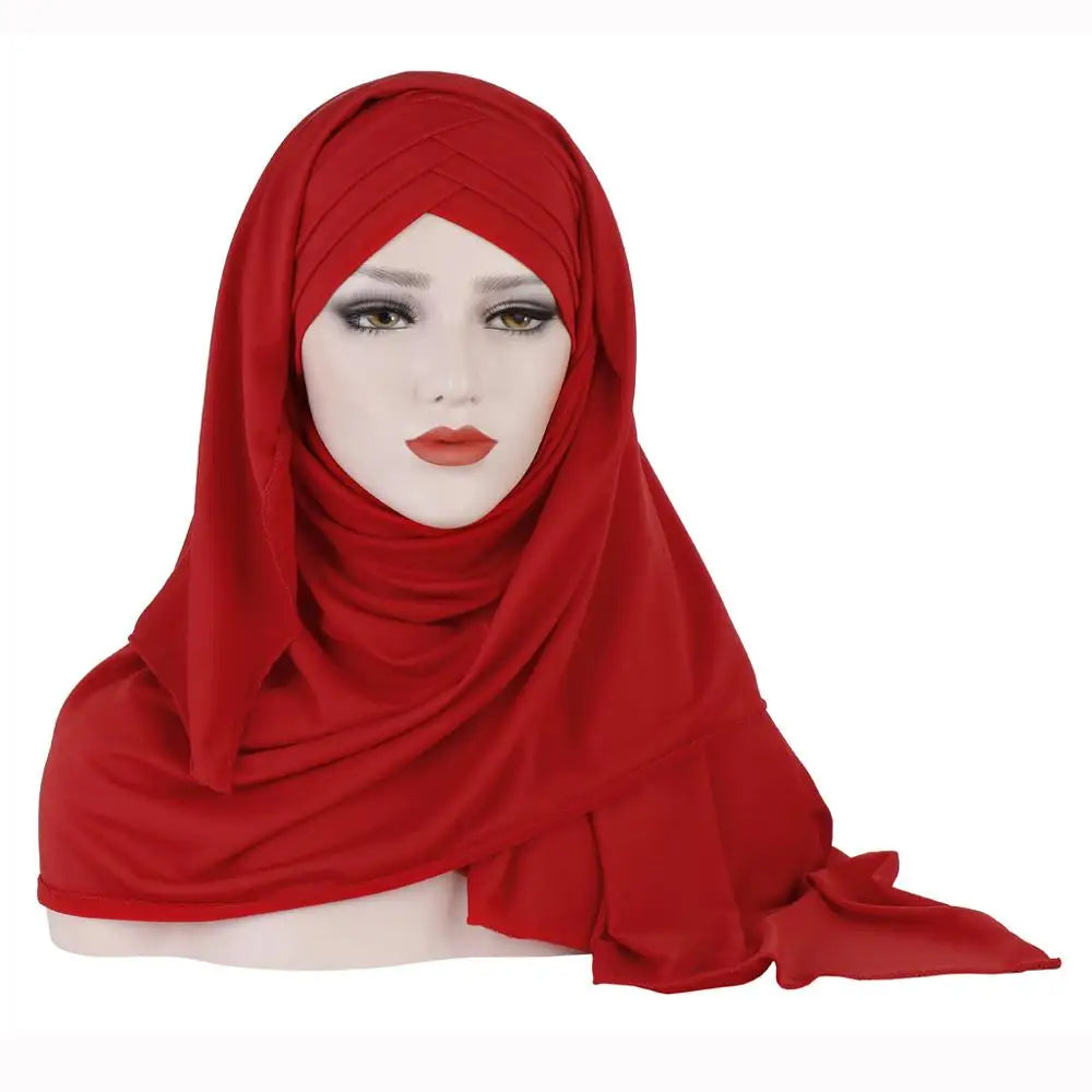 Un modèle portant un foulard de jersey de coton rouge vif drapé sur sa tête et ses épaules.
