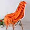 Un chal de cachemira naranja drapeado sobre una silla blanca.