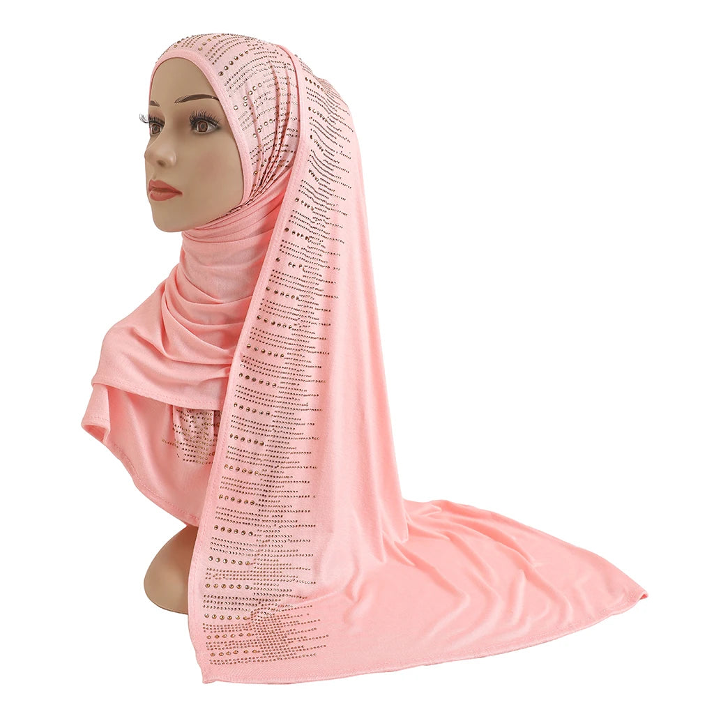 Étoffe de cachemire rose élégante avec des accents diamant, drapée autour de la tête et du cou d'un mannequin.