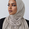 Une femme portant un foulard de jersey en coton beige avec un sous-voile noir et un maquillage foncé.