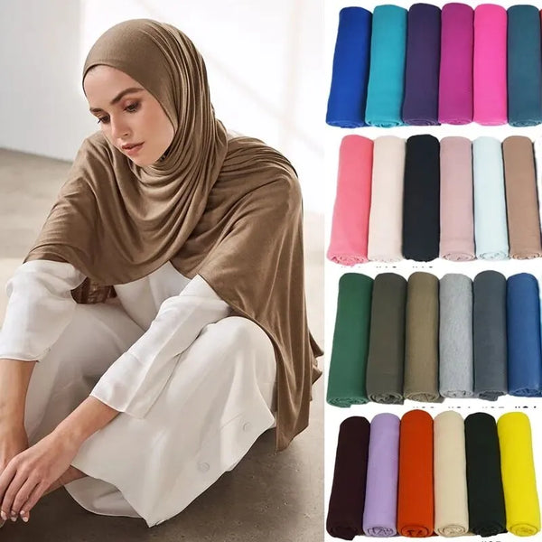 A woman wearing a beige hijab and white clothing is shown, with various colored cotton jersey scarves displayed below.