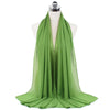 Un pañuelo de chifón verde esmeralda fluído drapeado sobre un maniquí.