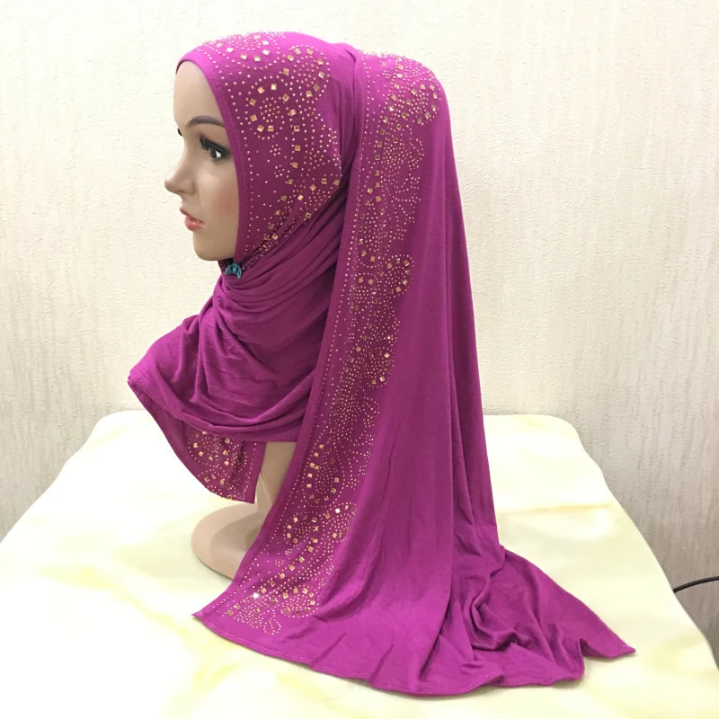 Écharpe de maillot magenta avec des ornements en cristal doré drapée sur un mannequin.