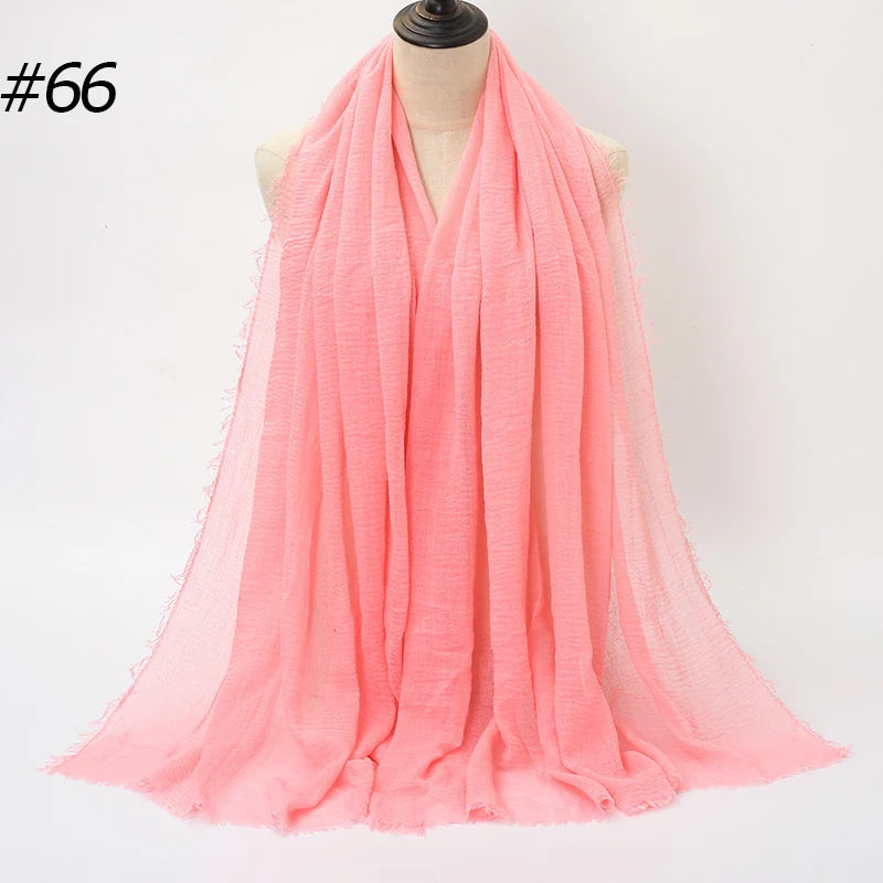 Helles korallrosa, gekräuseltes Baumwoll-Hijab-Schal um den Hals eines Mannequins drapiert.