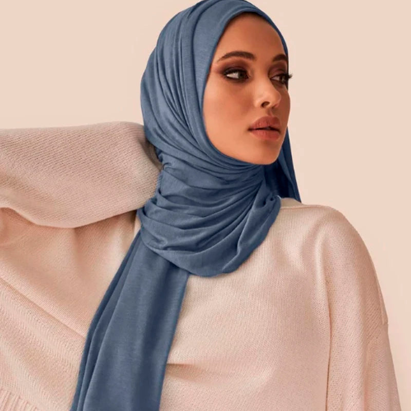 Une femme portant un foulard hijab en jersey bleu poussiéreux avec un haut rose pâle.
