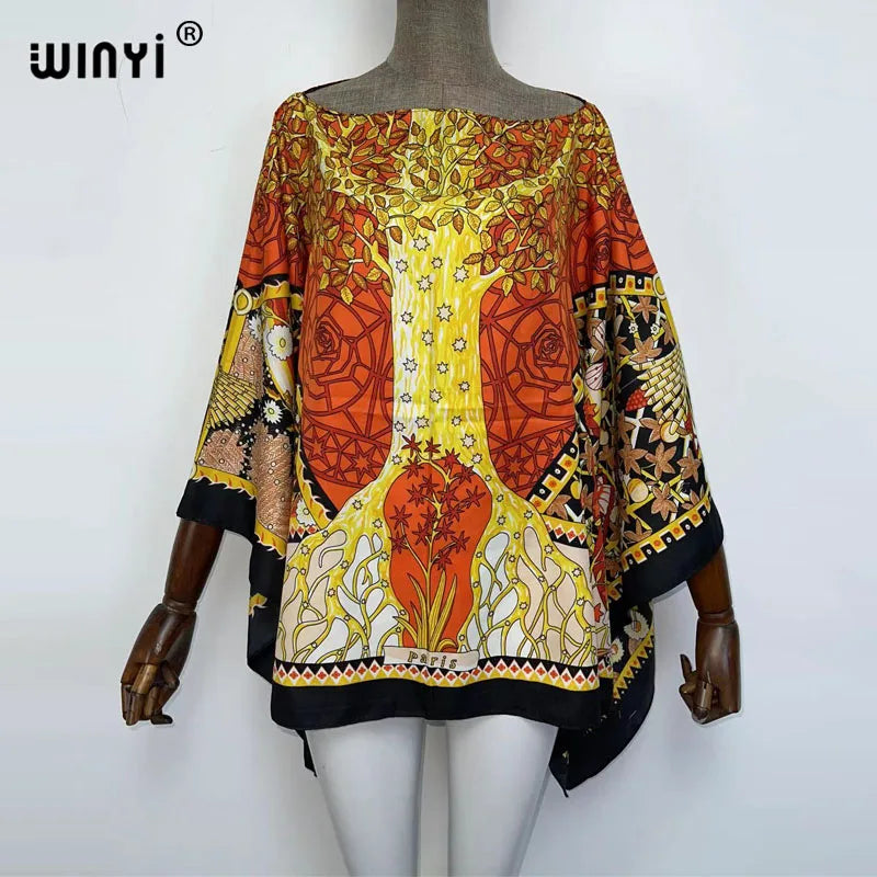 A woman models a colorful bohemian summer batwing abaya top featuring orange, yellow, and black patterns.