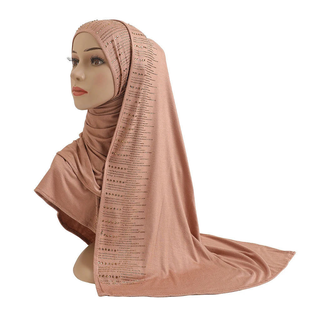 Une femme portant un foulard en jersey de coton élégant couleur pêche avec des accents de diamants drapé sur sa tête et ses é