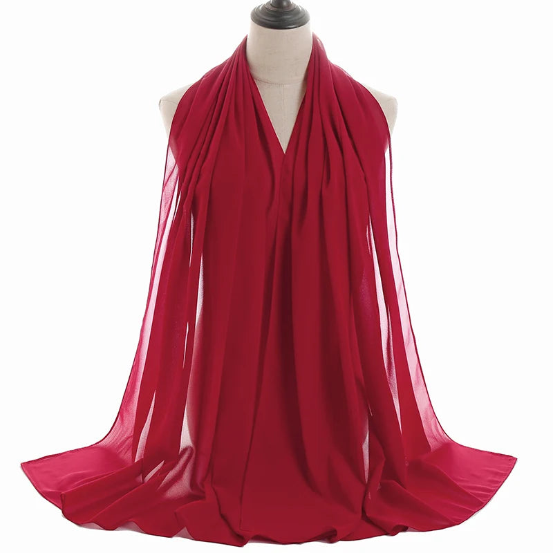 Un vibrante pañuelo de chifón rojo drapeado alrededor del cuello de un maniquí.