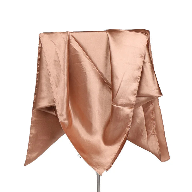 A draped solid color silk satin hijab scarf in a rosy nude tone.