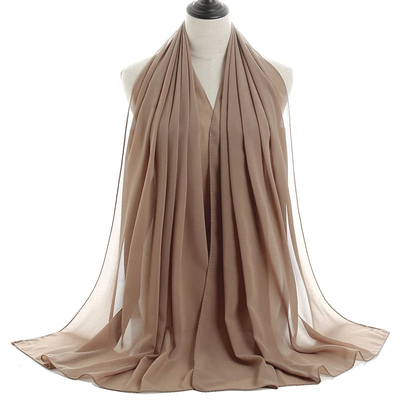 Un pañuelo de chifón beige drapeado alrededor del cuello y los hombros de un maniquí.