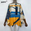 A model is wearing a colorful batwing abaya top featuring abstract patterns in blue, yellow, and cream tones.
