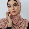 Une femme portant un foulard de jersey en coton couleur rose poudré avec un haut noir.