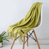 Una chal cashmere verde lima drapeada sobre una silla de madera.