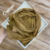 Eng zusammengerollter, fester, kamelfarbener Chiffon-Hijab-Schal in einem weißen Rahmen.