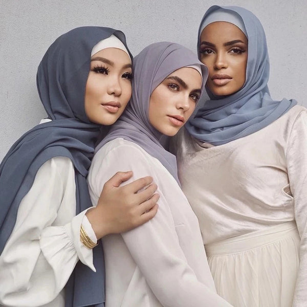 Three women wearing elegant solid chiffon hijab scarves in shades of gray and white.