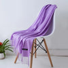 Una bufanda de cachemira morada drapeada sobre una silla blanca.