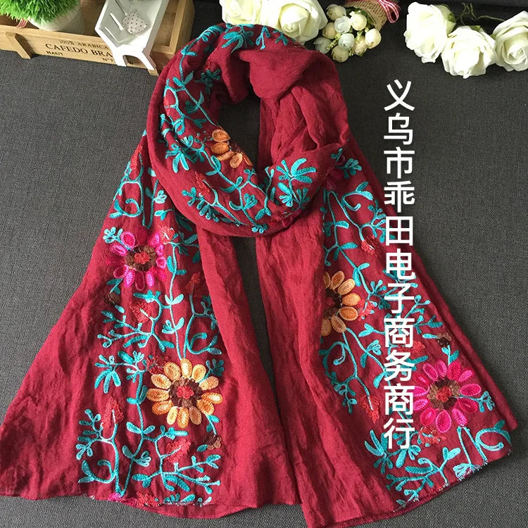 Tiefrote, bestickte Winter-Schal mit Blumenmuster, drapiert auf dunkler Oberfläche.