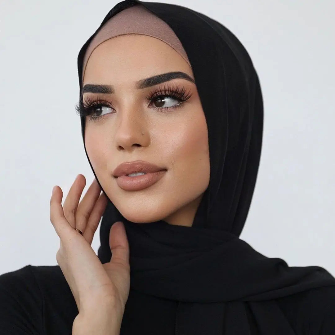 Une femme portant un élégant foulard hijab en jersey noir, regardant sur le côté.