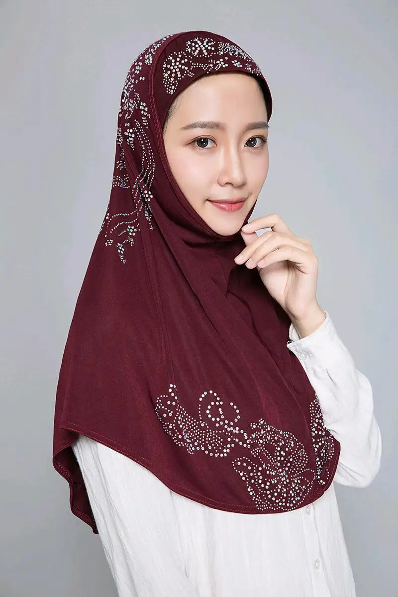 Eine Frau trägt einen kastanienbraunen Strass-Hijab über einem weißen Oberteil.