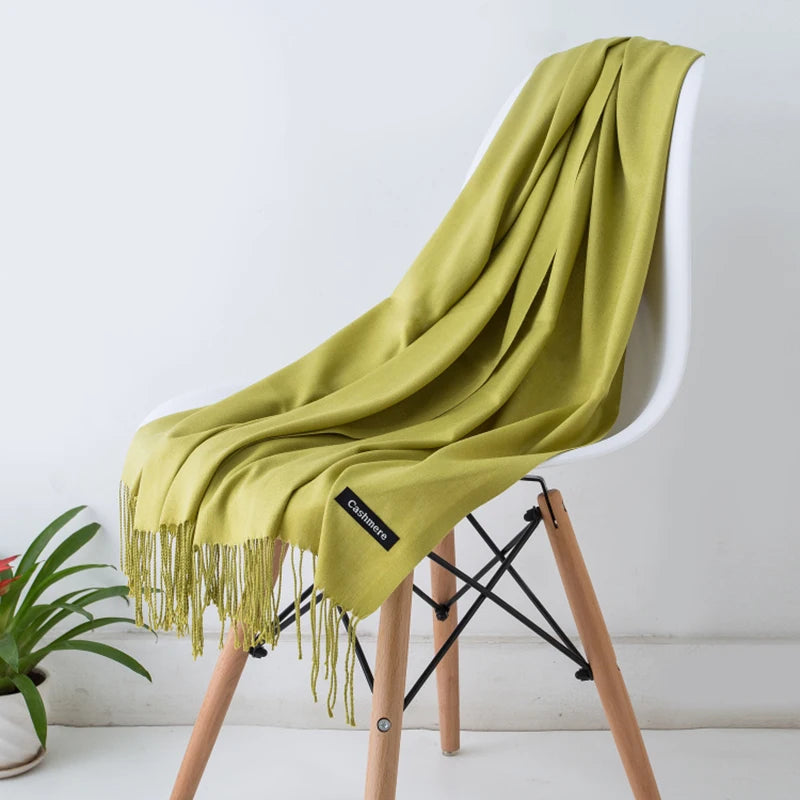 Una estola de cachemira verde lima drapeada sobre una silla de madera blanca.