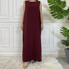 Marooner ärmelloser, schlichter Kaftan-Kleid auf einem Mannequin vor einer weißen Paneelwand.