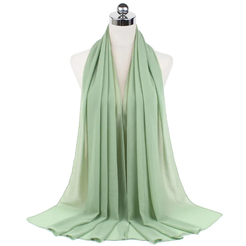 Pañuelo de chifón verde salvia ligero drapeado alrededor del cuello de un maniquí.