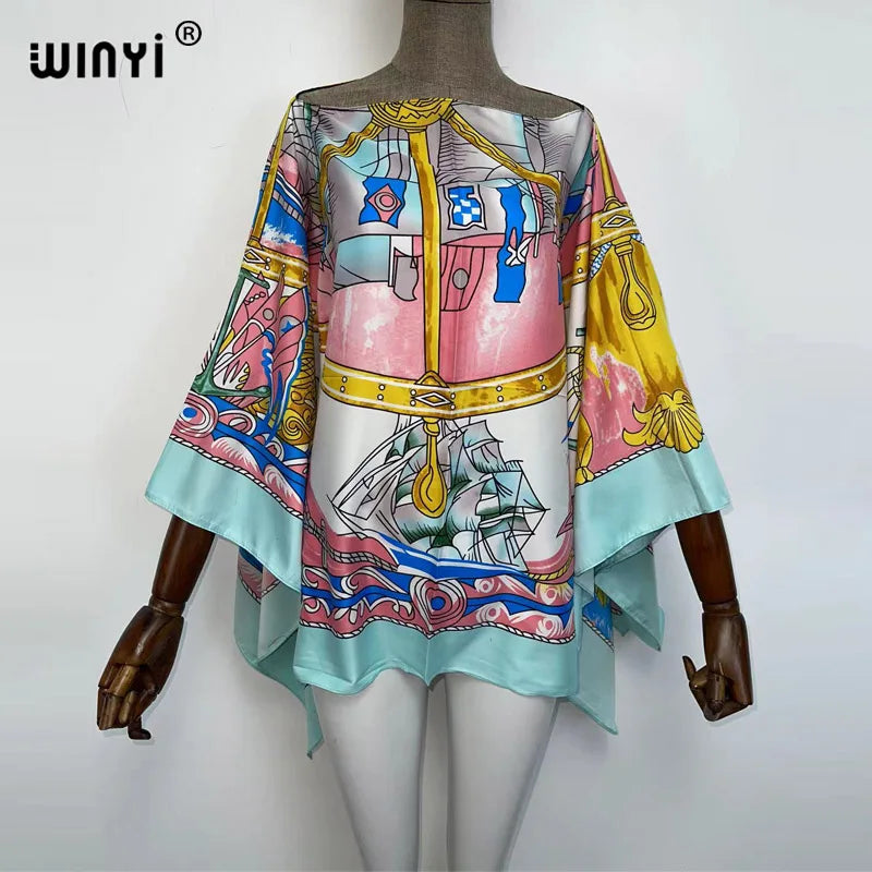 A woman models a colorful bohemian summer batwing abaya top featuring pink, blue, and yellow patterns.