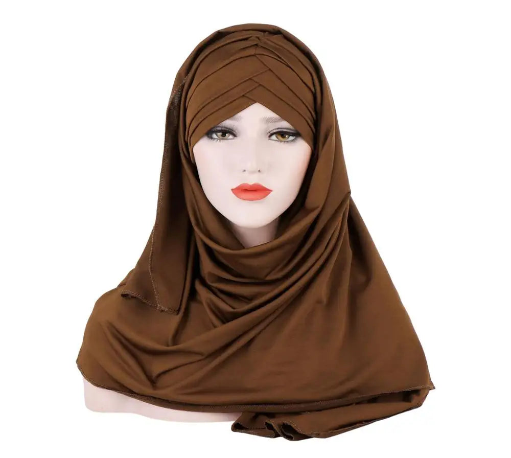 Un modèle portant un foulard en jersey de coton brun drapé sur sa tête et ses épaules.