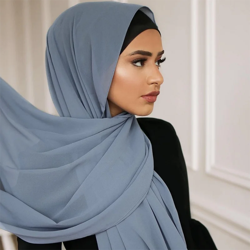 Eine Frau trägt einen hellblauen Chiffon-Hijab über Kopf und Schultern.