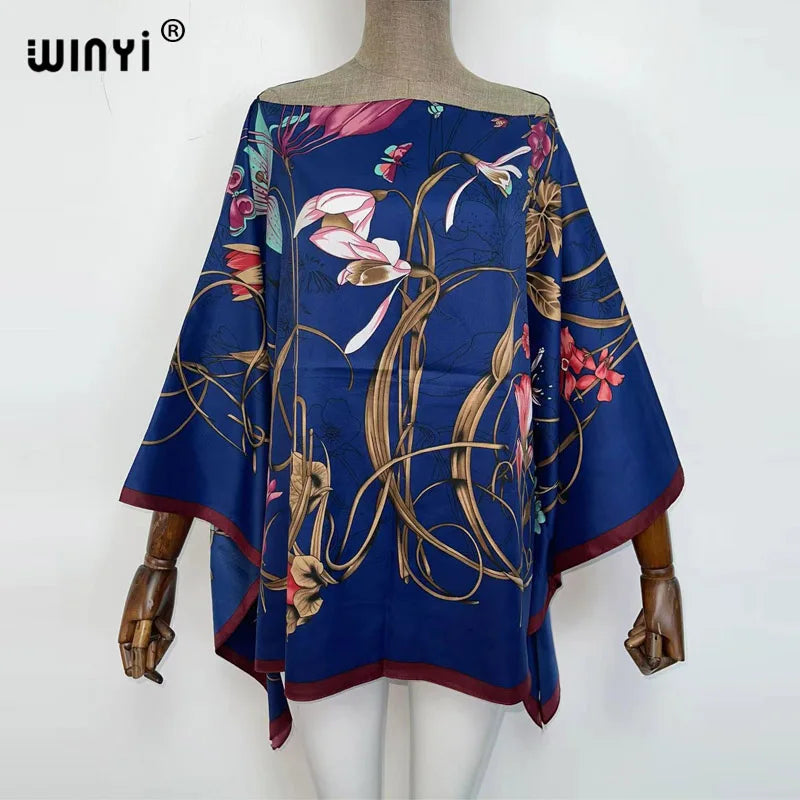 A dark blue batwing abaya top featuring floral embroidery and flowing fabric displayed on a mannequin.
