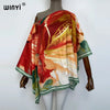 A woman is wearing a flowing, colorful batwing abaya top with warm tones of red, orange, and green.