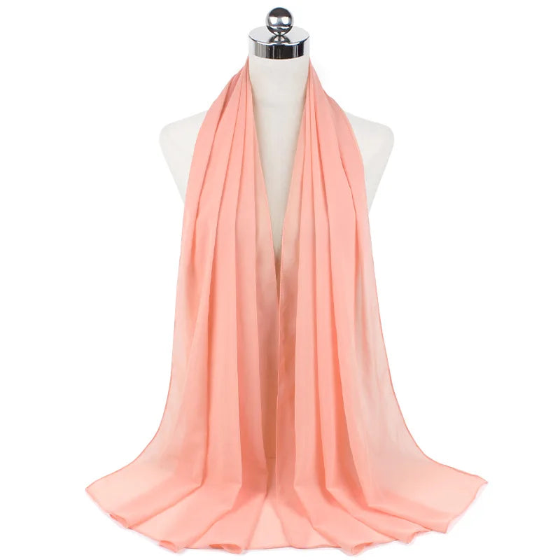 Pañuelo de chifón color melocotón drapeado alrededor del cuello de un maniquí.