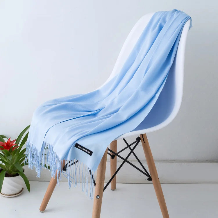 Una estola de cachemira azul claro drapeada sobre una silla de madera.