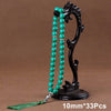 Black agate prayer beads on a stand with a green tassel necklace