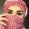 Nahaufnahme einer Frau mit roter-weißer karierter Chiffon-Hijab-Schärpe, die ihr Gesicht bedeckt.