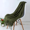 Una bufanda de cachemira verde oliva oscura drapeada sobre una silla blanca.