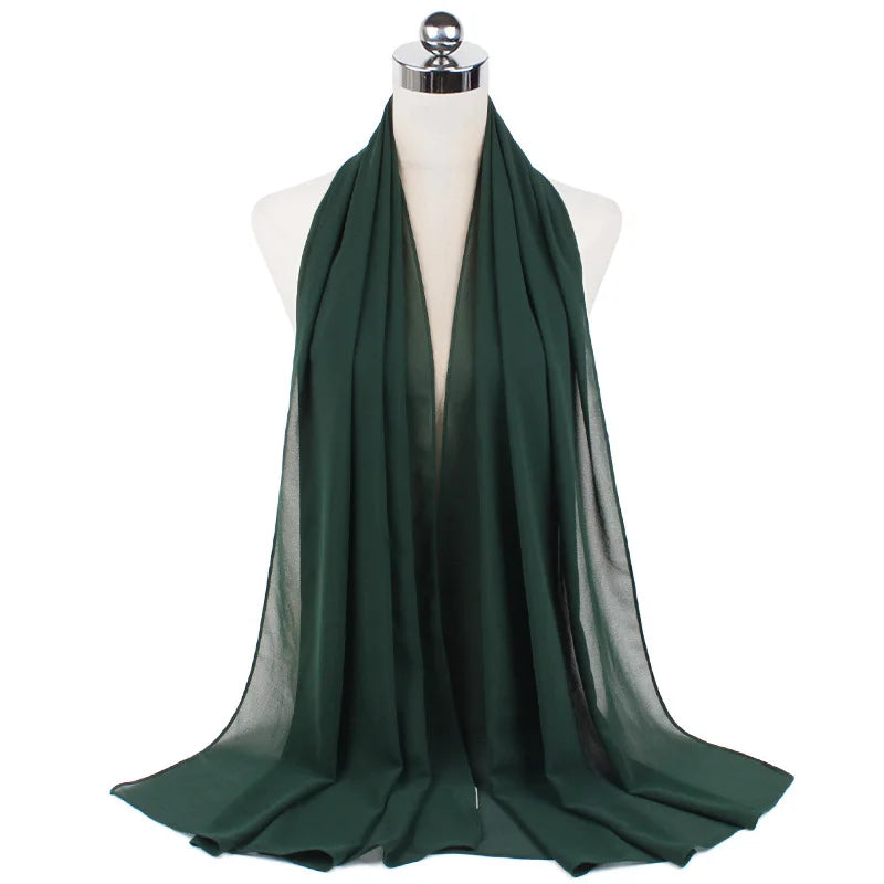 Bufanda hijab de gasa verde esmeralda oscura drapeada sobre un maniquí.