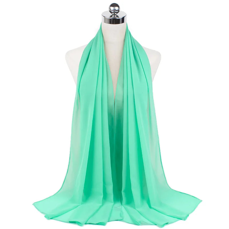 Un pañuelo de chifón verde menta brillante drapeado alrededor del cuello de un maniquí.