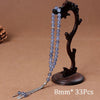 Black agate prayer beads on a wooden stand with a tassel necklace