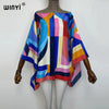 A model is wearing a colorful batwing abaya top with geometric patterns in shades of blue, pink, yellow, and orange.