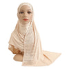 Une femme modèle une écharpe en jersey de coton beige clair avec des accents diamantés drapée sur sa tête et ses épaules.