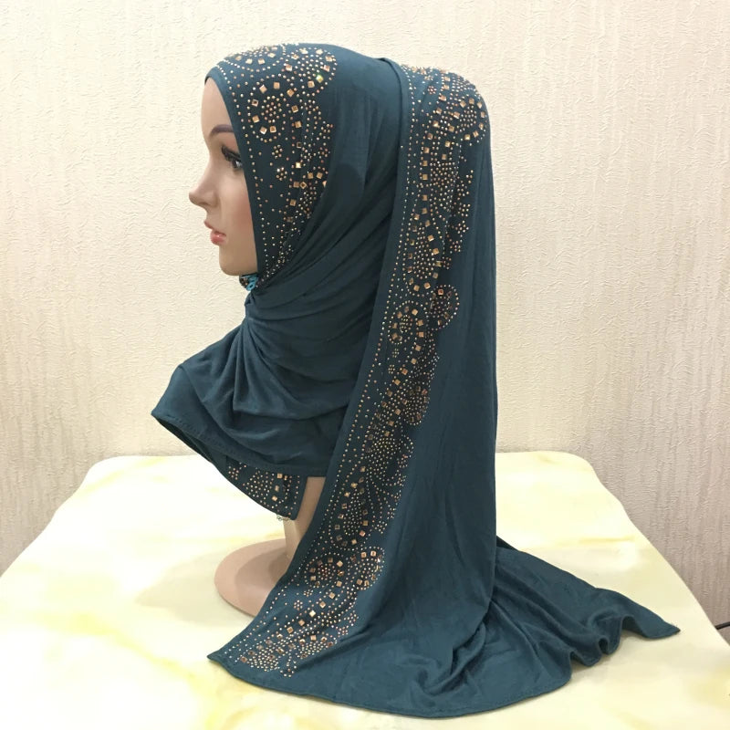 Écharpe de maillot de couleur sarcelle foncé avec des embellissements de cristaux dorés drapée sur un mannequin.