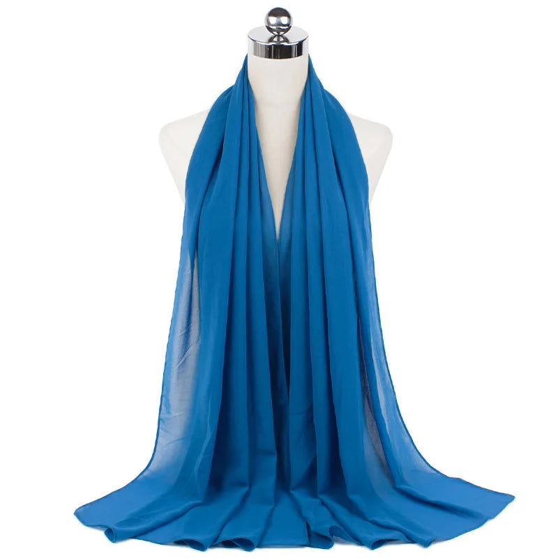 Un pañuelo de chifón azul brillante drapeado alrededor del cuello de un maniquí.