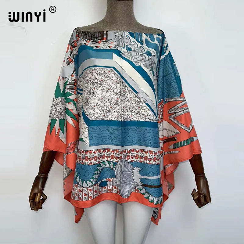 A woman models a colorful bohemian summer batwing abaya top featuring abstract patterns in teal, orange, and white.