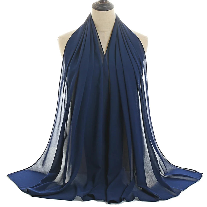 Un pañuelo de chifón azul oscuro drapeado alrededor del cuello y los hombros de un maniquí.