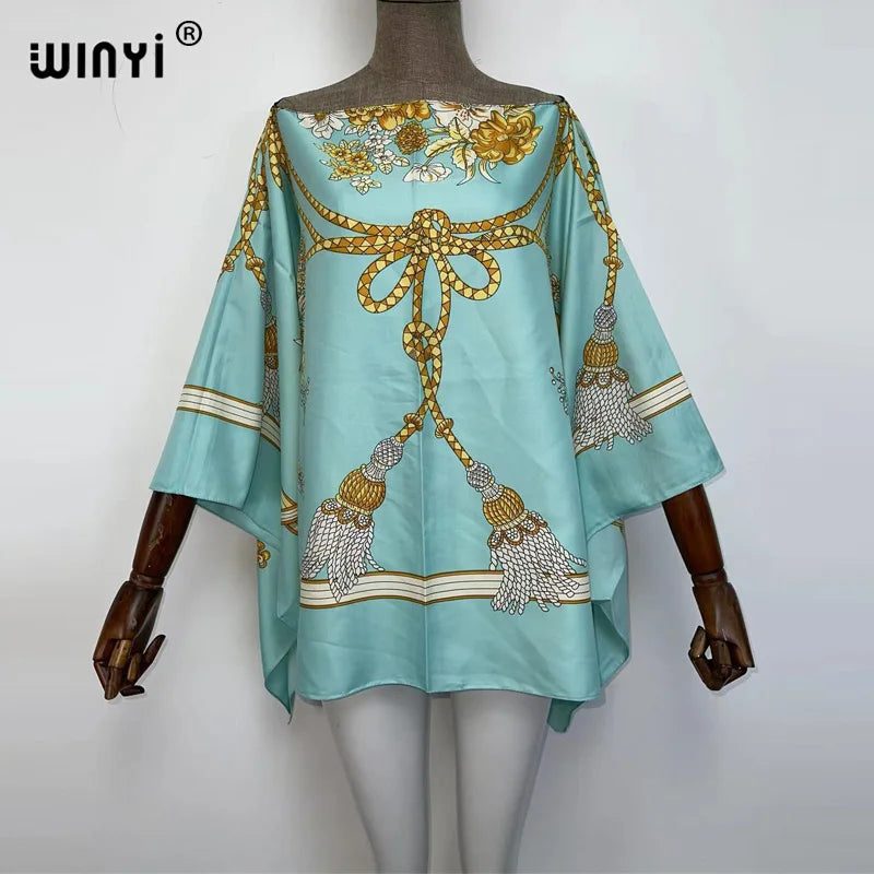 A light blue batwing abaya top featuring gold embroidery and tassels on the front